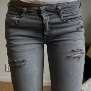 Grå Diesel bootcut jeans med slitningar - Gråa jeans med bootcut passform och snygga slitningar på låren och knäna. 