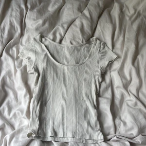 Vit ribbad topp från JDY - Säljer en vit ribbad topp från JDY i storlek XS. Toppen har korta ärmar, rundad halsringning och är tillverkad i ett mjukt, stretchigt material. Perfekt för en clean och enkel look med snygga vertikala ränder.