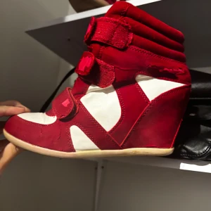 Röda och vita sneakers med kilklack - Snygga röda och vita sneakers med kilklack och kardborreband. De är lite slitna och färgen kan åka av lätt men sitter bra på och har en stabil klack. Storlek 38❤️