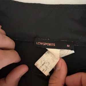 Svarta leggings från LCWSPORTS M - Svarta leggings från LCWSPORTS i storlek M. De har en snygg meshdetalj på benen och en smal passform som sitter tight. Perfekta för träning eller chill dagar. Materialet är stretchigt syntet och de har en enkel, sportig look.