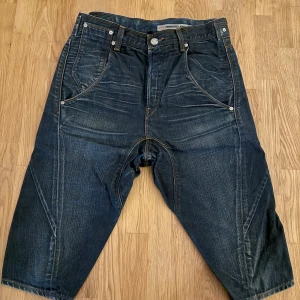 Levi's Engineered Jeans shorts, mörkblå - Säljer ett par Levi's Engineered Jeans shorts i mörkblå denim med coola sömdetaljer och klassiska fem fickor. De har en loose passform och midwaist, med snygga slitningar och kontrastsömmar. Perfekta för dig som gillar streetwear och unik design.