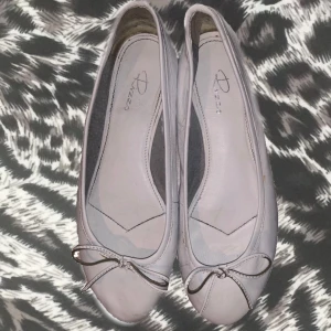 Vita ballerinaskor med rosett från Rizzo - Söta vita ballerinaskor från Rizzo i mjukt skinn med rund tå och dekorativ rosett framtill. De är i perfekt skick utan några defekter, köpta online och tycker verkligen om dom så mycket men de passar tyvärr inte mig. Perfekta att styla med jeans eller klänning för en fräsch och klassisk look. Platt sula för skön komfort hela dagen.