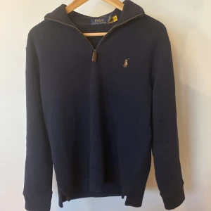 Mörkblå half zip tröja Polo Ralph Lauren  - Mörkblå långärmad tröja från Polo Ralph Lauren med klassisk broderad logga på bröstet. Tröjan har half zip-dragkedja och är tillverkad i mjuk bomull. Perfekt för lager-på-lager och snygg till jeans eller chinos.