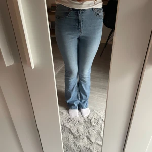 Bootcut jeans i ljusblå denim H&M - Snygga bootcut jeans från H&M i ljusblå denim. Hög midja och klassisk femficksmodell. Jeansen har en lätt utsvängd passform nertill och är tillverkade i bomullsmix. Perfekta för dig som gillar en retroinspirerad look.