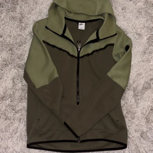 Nike hoodie i två nyanser av grönt - Nike hoodie i två olika gröna nyanser med svart logga på bröstet. Tröjan har hel dragkedja, huva och långa ärmar. Snygga svarta detaljer längs dragkedjan och på ärmen. Perfekt för chill eller träning. Hör av er om ni vill ha fler bilder!. Pris kan diskuteras.