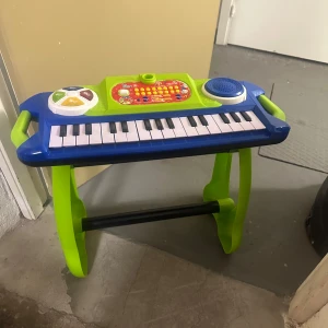 Barns Piano  - Ingen bok syns på bilden, utan det är ett leksakspiano med färgglada knappar och tangenter. Perfekt för unga musikälskare som vill utforska ljud och skapa egna melodier. 