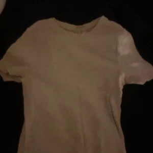 Vit ribbad t-shirt från H&M Divided - En basic vit t-shirt från H&M Divided i storlek XS. T-shirten är ribbad, har rund halsringning och korta ärmar. Perfekt att matcha med jeans eller kjol för en clean och enkel look.