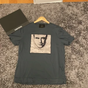 mörkgrön t-shirt med svart motiv - Snygg mörkgrön t-shirt från Limitato med svart konstnärligt motiv och svart kant. t-shirten har en kvadratisk form och känns riktigt lyxig och stilren, perfekt att ha för en cool touch.