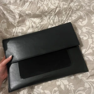 Svart dator/ kuvert Väsk från Carin Wester  - Aldrig använd stilren svart dator / kuvertväska från Carin Wester i skinn med slät finish och en diskret logga framtill. Väskan är 34 cm bred och har ett stort fack samt en praktisk ficka på framsidan. Perfekt för att bära med sig det viktigaste med snygg och minimalistisk look.