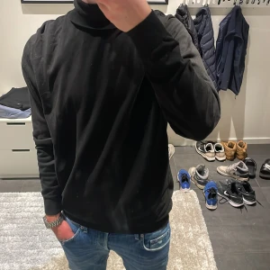 Svart polotröja i bomull från Zara - Svart polotröja i bomull från Zara. Modellen på bilden är ca 180 cm lång. Hör av dig vid funderingar!