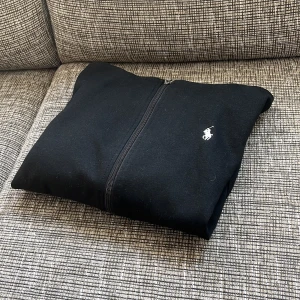 Ralph Lauren zip hoodie - Säljer en svart Ralph lauren zip hoodie med vitt märke och snören kvar