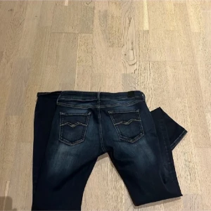 Mörkblå Replay jeans, midwaist, 29/32 pris inte hugget i sten. - Snygga mörkblå jeans från Replay med klassisk femficksdesign och diskreta slitningar. Modellen har raka ben och normal midja. Jeansen har detaljerade bakfickor med broderi och är tillverkade i ett stretchigt denimtyg för skön passform.