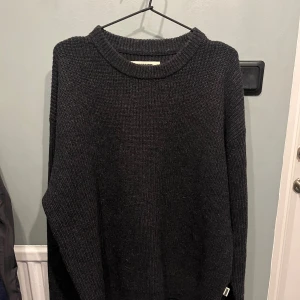 Svart stickad tröja från Woodbird - Mysig svart stickad tröja från Woodbird i storlek L, med grov ribbstickad struktur och rund halsringning. Perfekt för lager-på-lager och chill dagar. Långärmad och loose fit för en avslappnad vibe. Perfekt nu då kylan börja krypa fram.😁