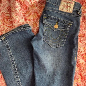 True Religion Joey Low Rise Flare Jeans - Säljer ett par blå True Religion Joey jeans med låg midja och utsvängda ben. Jeansen är andvända väldigt fåtal gånger och är i helt nytt skick. Nypriset på jeansen ligger på 1399