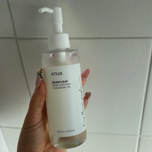 Anua Heartleaf Cleansing Oil 200ml - Anua Heartleaf Pore Control Cleansing Oil i genomskinlig plastflaska med vit pump. Oljan är lätt och genomskinlig, perfekt för att ta bort smink och rengöra porer. Använd