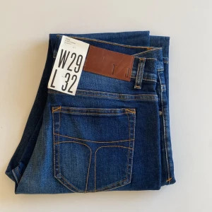 Tiger of Sweden blå jeans W29 L32 - Snygga blå jeans från Tiger of Sweden med klassisk femficksdesign och kontrastsömmar. Modellen har rak passform och normal midja, tillverkade i slitstarkt denim med skinnpatch bak. Perfekta för dig som gillar stilrena och tidlösa jeans. Aldrig använd 