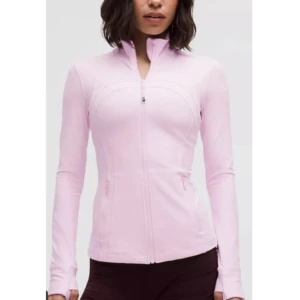 Lululemon Define Jacket Nulu Cropped  - Supersnygg ljusrosa Define jacka från Lululemon. Endast använd 2 gånger så den är i fint nyskick och inga defekter, Den är cropped så att den är inte lika lång som första bilden, (jag kunde inte hitta original bilden på deras hemsida eftersom den var limiterad och inte säljs längre) färgen är lite olika i olika ljus men jag skulle säga att den inte är lika stark rosa som på bilden på hemsidan utan den är mer som bilden på mig/bild nr 2 📌Nypris var 1280kr
