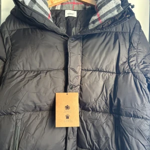 Vinter jacka - Fett burberry jacka med röda strip, passar perfekt till vinter. Har borttagbarra armar. I mycket bra skick. Storlek M-l. Sckickar samma dag.