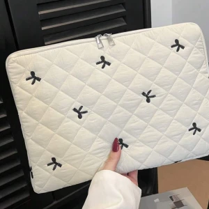 Quiltad vit datorväska med rosetter - Superfin quiltad datorväska i vitt med svarta broderade rosetter. Väskan har dragkedja upptill och ett mjukt, vadderat material som skyddar din laptop. Perfekt för dig som vill ha en söt och stilren look. Helt oanvänd då jag köpt ett annat, passar min dator som är 13 tum. Från shein och ord pris 75kr