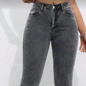 Gråa bootcut jeans med hög midja - Snygga grå jeans med bootcut-modell och hög midja. Jeansen har klassisk femficksdesign, dragkedja och knapp framtill. 