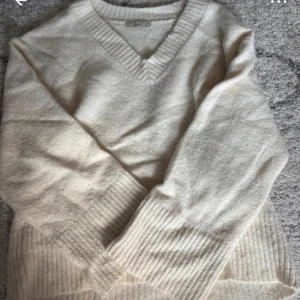 Vit stickad v-ringad tröja Gina Tricot - Mysig vit stickad tröja från Gina Tricot i v-ringad modell. Tröjan har breda ribbade muddar vid ärmslut och nederkant, samt en klassisk passform som funkar till allt. Perfekt för lager-på-lager under kyliga dagar.