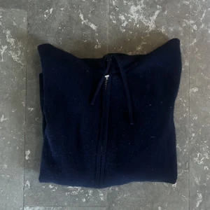 Mörkblå kashmirhoodie från Sayless - Riktigt snygg mörkblå hoodie från Sayless i lyxig kashmir. Tröjan har dragkedja framtill, huva med snörning och två fickor. Perfekt för dig som vill ha en stilren och bekväm look med premiumkänsla. Tyvärr passar ej tröjan mig längre och därav säljer jag den i mycket bra skick för mycket bra pris, hör av er vid frågor eller funderingar😀!
