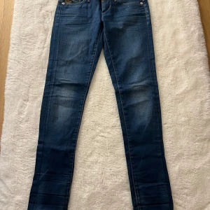 Mörkblå low waist skinny jeans från G-Star - Snygga mörkblå low skinny jeans från G-Star i klassisk femficksmodell. Jeansen har diskreta slitningar framtill och bakfickor med dekorativa sömmar. Tillverkade i stretchig denim för en tight passform och bekväm känsla.