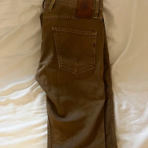 Beige Replay jeansbyxor 30/34 - Säljer ett par snygga beige jeansbyxor från Replay i klassisk rak modell. Byxorna har fem fickor, Replay-logga på bakfickan och patch i läder bak i midjan. Tillverkade i bomull för en skön känsla och stilren look.