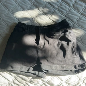 Svarta jeansshorts från Lindex - Svarta jeansshorts från Lindex i klassisk femficksmodell med bälteshällor och rå kant nedtill. Snygg och enkel design som funkar till allt, perfekt för dig som gillar en chill och stilren look. Passar dig som vill ha shorts med normal passform och midwaist.