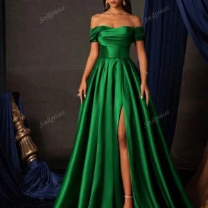 Grön offshoulder balklänning i satin - Elegant grön långklänning i glansig satin med offshoulder-modell och markerad midja. Klänningen har en snygg slits framtill och en vacker, svepande kjol. Perfekt för bal eller festliga tillfällen. Stilren och modern design med dragkedja i ryggen. Är i storlek XL men kan lätt sys till mindre storlek. Priset kan diskuteras 