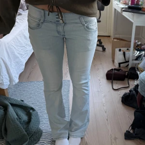 Lågmidjade Ljusblå bootcut jeans - Säljer ett par lågmidjade ljusblå jeans med bootcut-modell och låg midja. Jeansen har tre knappar framtill och en snygg dragkedjedetalj på bakfickorna. Klassiska fickor både fram och bak, tillverkade i stretchigt jeanstyg för skön passform. Midjemått: 37 cm innerbenslängden: 80cm💗