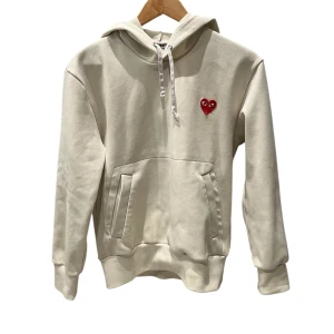 Vit hoodie Comme des Garçons Play - Säljer en beige hoodie från Comme des Garçons Play då den tyvärr är för liten för mig. Tröjan är i bra skick men är lite nopprig på vissa ställen. Det är dock inget man tänker på då det är så lite. Hör av er vid frågor eller funderingar!