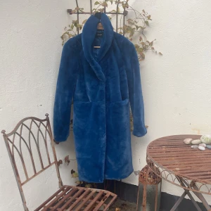 Blå pälsjacka från Vero Moda XS - Säljer en blå pälsimitation jacka från Vero Moda i storlek XS. Jackan är lång, har stora fickor framtill och en bred krage. Den är supermjuk och har ett lyxigt, fluffigt material som verkligen sticker ut. Perfekt för dig som vill ha en statementjacka i vinter.