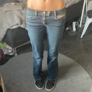 Bootcut jeans från ONLY, mörkblå - Mörkblå bootcut jeans från ONLY med slitna detaljer och fransade benslut. Klassisk femficksmodell med dubbla silverfärgade knappar och orange sömmar. Jeansen har en snygg tvätt och är tillverkade i jeansmaterial.