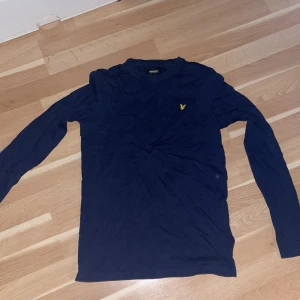 Marinblå långärmad tröja Lyle & Scott - Säljer en marinblå långärmad tröja från Lyle & Scott Junior. Tröjan har rund hals och den klassiska gula loggan broderad på bröstet. Perfekt basic till garderoben och skön att bära till jeans eller joggers.