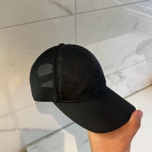 Gucci keps - Hej ! säljer denna Gucci Nylon keps, sällsynt modell, kepsen är i bra skick, påse och tags ingår vid köp, spännet är ej i bästa skick, men annars är kepsen utan defekter !