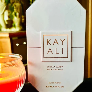 Kayali ”Vanilla Candy Rock Sugar”!EDP  - Trendande Kayali ”Vanilla Candy Rock Sugar” l 42 - Eau de parfum. 100 ml. Obruten förpackning.   Denna doft är söt, ljuvlig och spännande och en lättare och fräschare version av märkets kultdoft, Vanilla Candy 28.  Aromer från kanderade päron och bubbelgummi förstärker den fruktiga sötman av sötsaker med en explosion av förtrollande vanilj som hjärtnot. Den avrundas med varma och träiga noter av tonkaböna, sandelträ och patchouli. Söt, varm, kryddig  och förförisk.