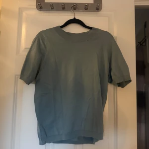 Ljusgrön stickad kortärmad tröja - En stilren ljusgrön stickad tröja med korta ärmar och rund halsringning. Perfekt för dig som gillar en enkel och clean look. Tröjan har ribbade detaljer vid hals, ärmslut och nederkant.