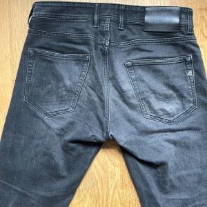 Replay Grover svarta jeans straight fit - Snygga svarta Replay Grover jeans i straight fit med klassisk femficksdesign och diskret Replay-logga på fickan. Jeansen har en mörk tvätt och är tillverkade i mjukt denimtyg som sitter skönt hela dagen. Kan diskutera pris då det finns nån fläck som lätt försvinner i tvätten