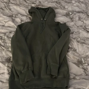 Grön oversized hoodie från H&M - Säljer en grön hoodie från H&M i oversized fit. Tröjan har huva med snörning, stor magficka och ribbade muddar vid ärmslut och nederkant. Perfekt för chill dagar och enkel att matcha med jeans eller mjukisbyxor.