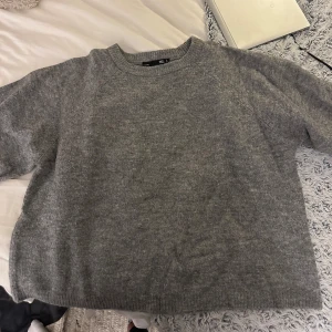 Grå stickad tshirt från lager 157 - Mysig grå stickad tshirt med rund halsringning och avslappnad passform. Perfekt för kyliga dagar och enkel att matcha med jeans eller kjol. 