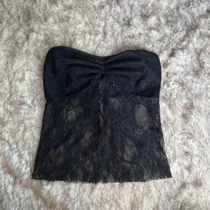 Svart spets bandeau tubtopp med snörning - Säljer en svart bandeau tubtopp i spets och snörning baktill. Ej orginalsnöre