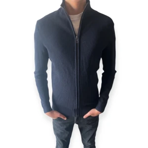 Mörkblå stickad cardigan jacka - Snygg mörkblå stickad cardigan jacka med hel dragkedja framtill och hög krage. Jackan har en clean look utan synliga loggor, ribbade muddar och lång ärm. Perfekt för dig som gillar stilren och enkel design. (Modellen är 178 cm)