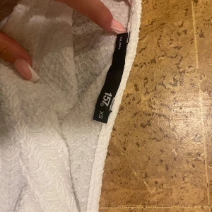 Vit långärmad tröja från 157 - Säljer en vit långärmad tröja från 157 i storlek XS. Tröjan har ett snyggt strukturerat mönster i tyget och är tillverkad i ett mjukt material som känns skönt mot huden. Perfekt att styla med jeans eller kjol för en clean look.