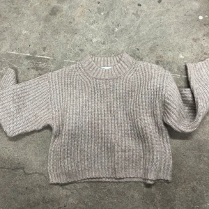 Beige stickad croppad tröja från 157 - Supermysig beige stickad tröja från 157. Modellen är croppad med bred ribbad kant i halsen, ärmslut och nederkant. Perfekt för lager-på-lager och passar till allt. Snygg och enkel att styla till både jeans och kjol.🩷Strl 140 & Knappast använd!! 