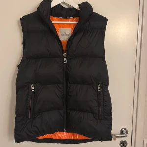 Svart dunväst från Moncler - Svart dunväst från Moncler med glansig orange insida. I storlek 2 passar en medium/ large. Finns original tagg på den däremot finns inte kvitto. Är annars i bra skick. Tänkte 2500kr 