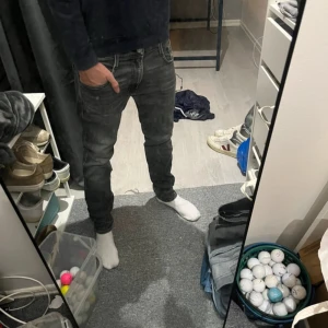 Replay Anbass svarta slim jeans 31/32 - Säljer ett par svarta Replay Anbass jeans i slim fit. Jeansen har klassisk femficksdesign, snygga slitningar och en mörk tvätt. Materialet är en stretchig bomullsblandning som sitter skönt och följer kroppen. Perfekta för dig som gillar en smalare passform. Negativt=hål i skrevet men syns inte vid användning och går att sy igen 