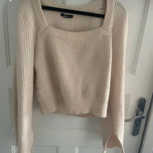 Beige stickad tröja Gina Tricot - Supermysig beige stickad tröja från Gina Tricot med fyrkantig halsringning och långa ärmar. Tröjan har ribbad struktur och är lite croppad i modellen, perfekt för att få en chill och snygg look. Passar dig som gillar enkel och stilren design.