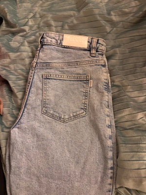 Ljusblå jeans från Wow Denim - Säljer ett par ljusblå jeans från Wow Denim med klassisk femficksdesign, hög midja och raka ben. Jeansen har fransade benslut för en cool och avslappnad vibe. Materialet är klassisk denim och passformen är normal.