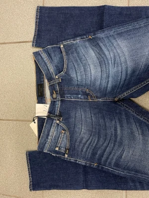 Slim fit jeans från Tiger of Sweden - Snygga blå jeans från Tiger of Sweden i slim fit-modell. Jeansen har klassisk femficksdesign, orangea kontrastsömmar och en mörk tvätt med lätt slitning framtill. Tillverkade i bomull med en skön passform som sitter tajt men ändå bekvämt.